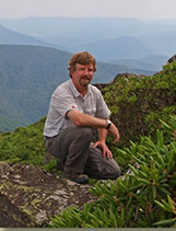 Tom Ranney knealing with mountains in the background